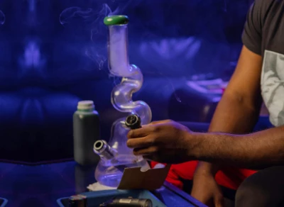 A person cleaning a glass bong with a brush, demonstrating the steps for achieving a sparkling clean bong.