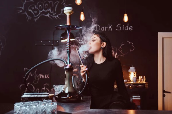 A girl smoking a hookah, representing the lifestyle and products associated with starting a smoke shop business.