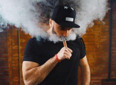 Man using a vape device, exhaling vapor