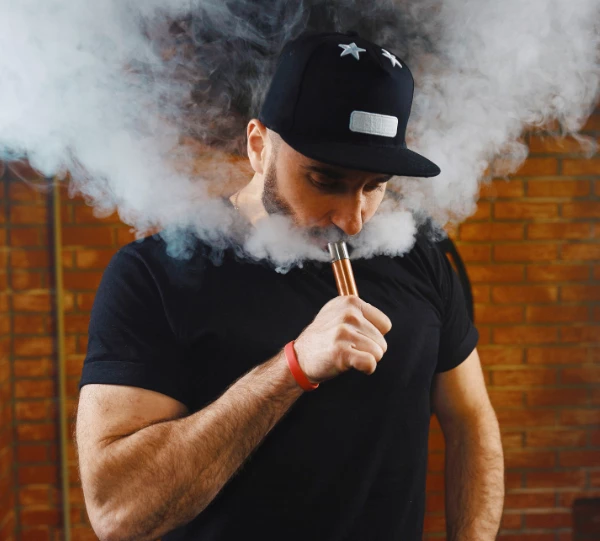 Man using a vape device, exhaling vapor