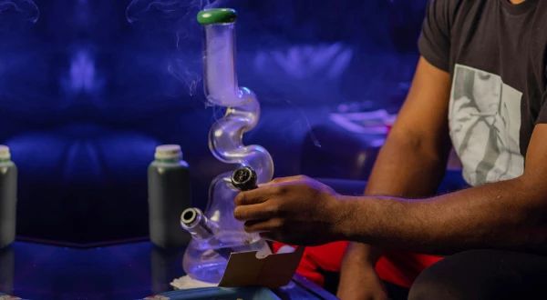 A person cleaning a glass bong with a brush, demonstrating the steps for achieving a sparkling clean bong.